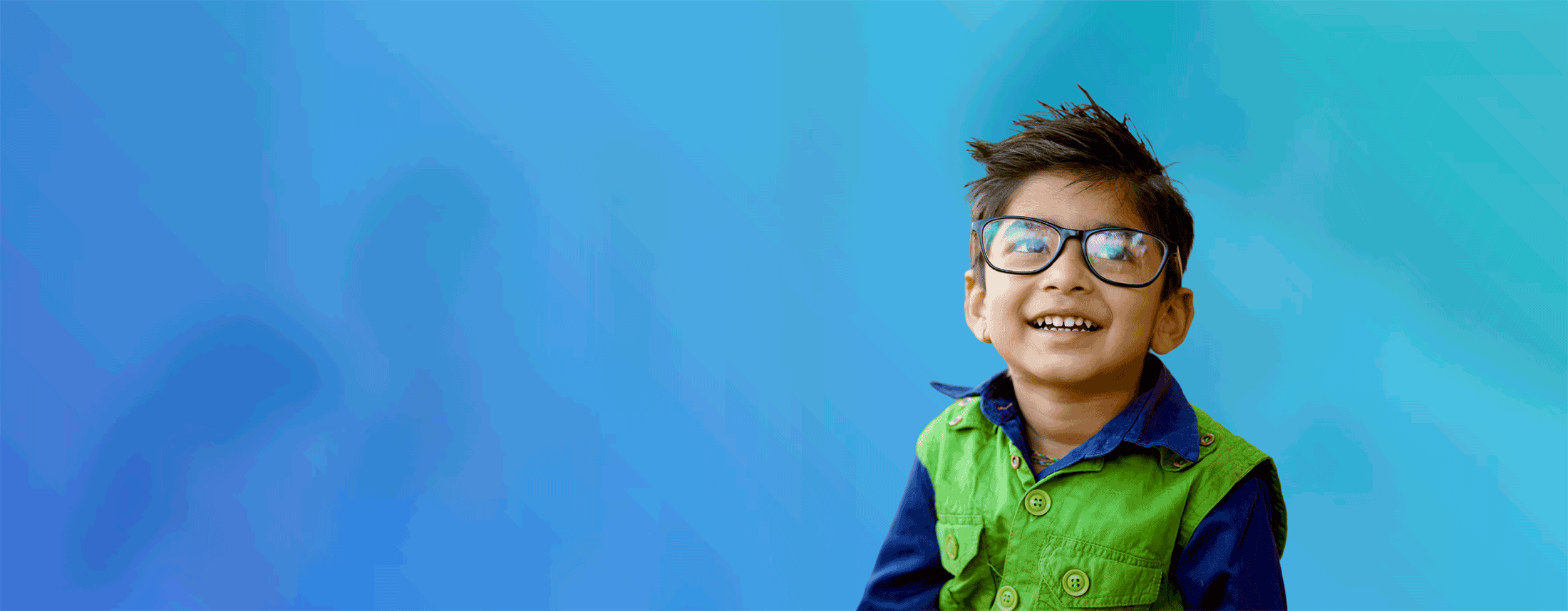 image of adolescent boy wearing a green and blue button down collared shirt and black glasses looking up and smiling